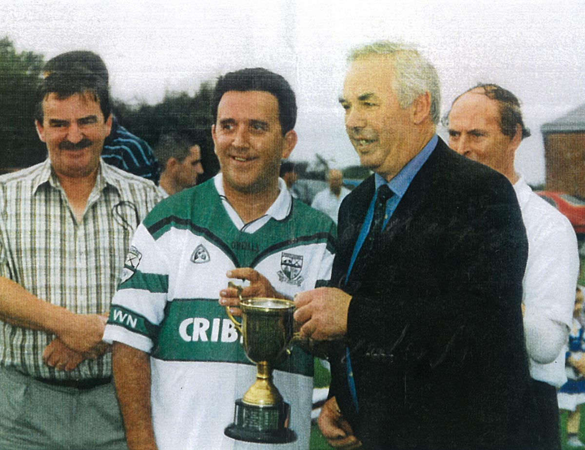 Liam (Stapo) Brown, team captain, receives the JFC “C”
trophy from county chairman, Dick Miller, in 2003, with
Brendan (Sonny) Keogh enjoying the victory